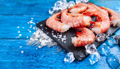 King prawns with pieces of ice on a blue background with copy space. Shrimps without a head on a...