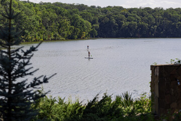 Fototapeta na wymiar Women float on Sapah on the lake in the park. Outdoor recreation, healthy lifestyle.