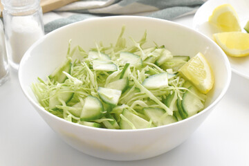 Cucumber and cabbage salad in a white bowl.  Healthy green salad. 