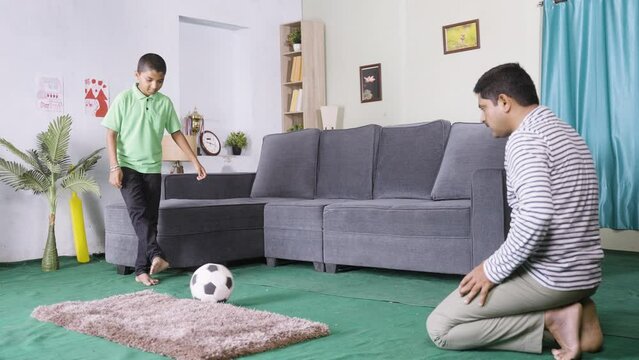 wide shot of father and kid playing football at home during weekend holiday - concept of bonding, family and game practice