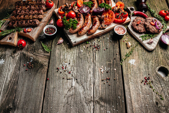 Barbeque menu. Grilled meat assortment of tasty bbq snacks with vegetables on wooden board. banner, menu, recipe place for text, top view