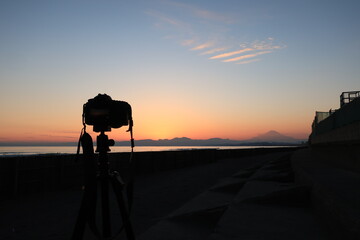 鵠沼海岸から見る伊豆半島に沈む夕日と富士山とカメラのシルエット