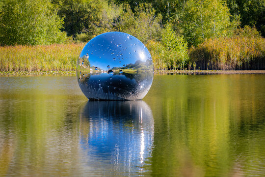 Taraspsee, Switzerland - September 24, 2022: The floating metal ball on Taraspsee (Grisons, Switzerland) is an artwork from swiss artist Not Vital. It represents the moon, in which all is reflected.