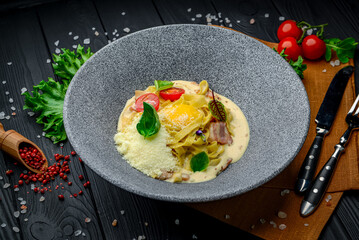 Pasta carbonara with tagliatelle spaghetti, egg yolk, bacon and basil.