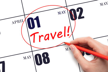 Hand drawing a red circle and writing the text TRAVEL on the calendar date 1 May. Travel planning.