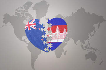 puzzle heart with the national flag of new zealand and cambodia on a world map background. Concept.