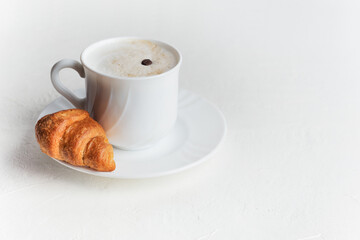 Coffee cup and fresh croissant layout on a white background. The concept of healthy eating and sweet food. French breakfast. View from above. Design element