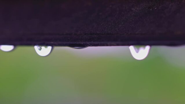 Macro view of falling raindrops from  window frame of skylight during rain. Sweden.