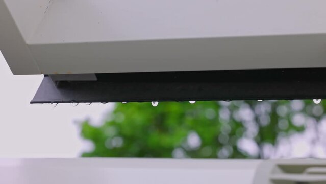 Close up view of falling raindrops from  window frame of skylight during rain.