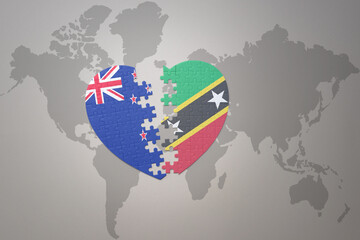 Obraz premium puzzle heart with the national flag of new zealand and saint kitts and nevis on a world map background. Concept.