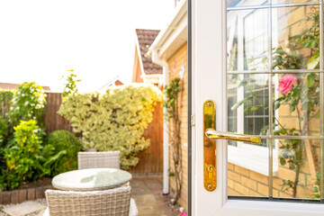 Shallow focus of a newly fitted double glazed door showing the ornate door handle and leaded window. Seen exiting into a patio area of a back garden. - obrazy, fototapety, plakaty