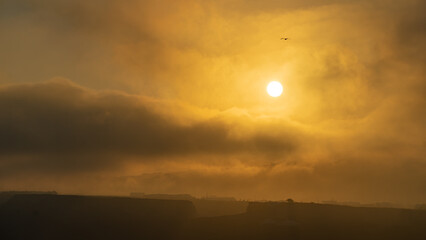 Sunrise with golden mist over the town of Akrotiri on Santorini island