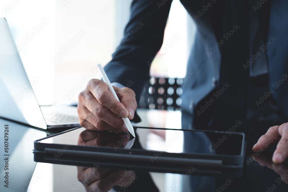 Poster businessman using stylus pen signing e-document on digital tablet with laptop computer on table at o