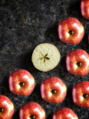 Pattern of red apples and slice of apple with star on black concrete background with copy space. Creative flatlay with summer fruit.