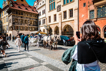 PRAGUE, CZECH REPUBLIC April 1, 2022: Wedding carriage with horses on center of city at Old Town Square. Curious passers-by taking pictures - obrazy, fototapety, plakaty