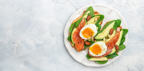 toast with avocadoo, salmon and spinach, nuts, sunflower seeds. Healthy, clean eating. Vegan or gluten free diet. Long banner format. top view