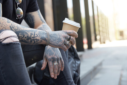 Tattooed man on the streets holding cup of coffee