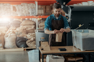 Uniformed worker packs roasted coffee beans into packages for sale