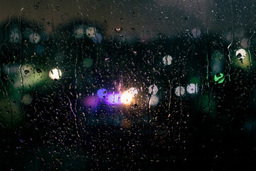 Obraz na płótnie Canvas water droplets and night lights on the glass