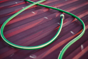 Close-up of a watering hose on a red roof in a garden.