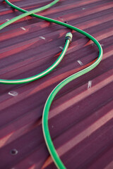 Close-up of a watering hose on a red roof in a garden.