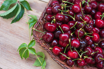 Ripe red cherries in a bowl and next to it on wooden table