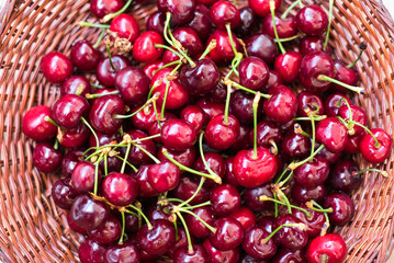 Ripe red cherries in a bowl and next to it on wooden table