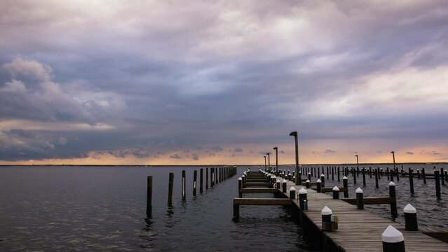 Time lapse of storm clouds getting lit up with sunset colors over a marina. Island Beach State Park New Jersey