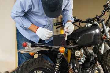 Man repairing motorcycle in repair shop, Mechanic fixing motorbike in workshop garage, Repairing...