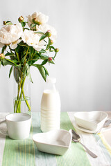 Breakfast with milk and cornflakes. white dishes and peonies on the table.