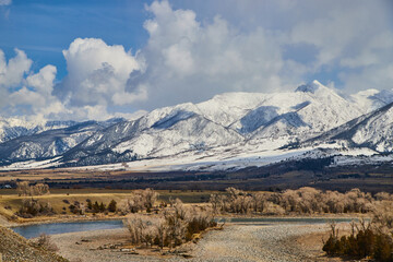 Beautiful white snowy mountains with spring fields and river in foreground