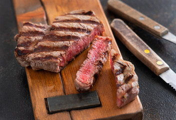 Grilled beef fillet steak with herbs and spices on dark table close up