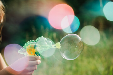 Dinosaur soap bubble gun shooter, blower. Party for kids. Girls,chidren playing funny family game with dad, father. Outdoors activity in summer in green park. Big flying bubbles