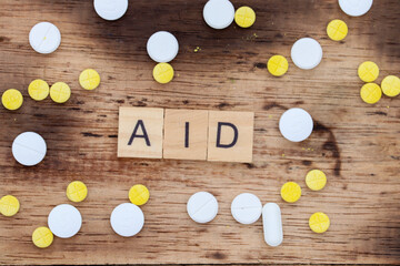 wooden block with the word aid written on it with a wooden backdrop and medicine