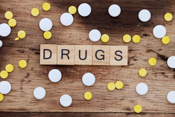 wooden block with the word drug written on it with a wooden backdrop and medicine