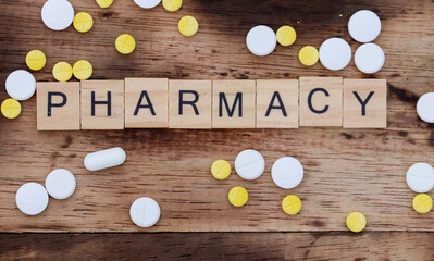 wooden block word concept with the word pharmacy, with wooden backgorund and white yellow tablet medicine