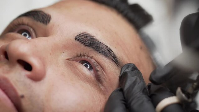 Close up shot of male microblading procedure to making permanent eyebrows makeup