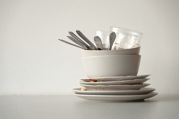 Stack of dirty dishes with food leftovers on the table after meal. Banquet ending concept. Unwashed...