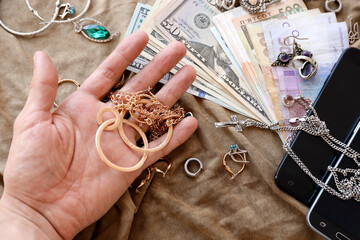 Marauders hand with bunch of stolen jewelry, money and smartphones on military uniform cloth...