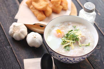 Congee in a Thai-patterned cup and fried batter served in an Asian-style cup on a black table with fried batter that we call 