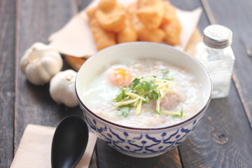 Congee in a Thai-patterned cup and fried batter served in an Asian-style cup on a black table with fried batter that we call 