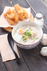 Congee in a Thai-patterned cup and fried batter served in an Asian-style cup on a black table with fried batter that we call 