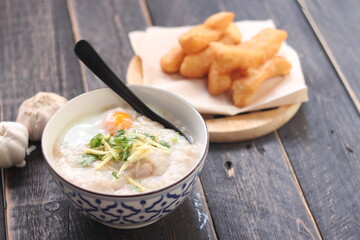 Congee in a Thai-patterned cup and fried batter served in an Asian-style cup on a black table with fried batter that we call 