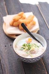 Congee in a Thai-patterned cup and fried batter served in an Asian-style cup on a black table with fried batter that we call 