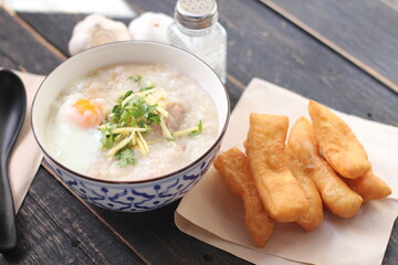 Joke or Congee in a Thai style cup Served on a black wooden table. It's an Asian breakfast.
