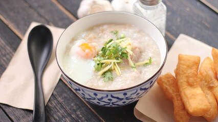 Joke or Congee in a Thai style cup Served on a black wooden table. It's an Asian breakfast.