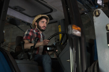 Obraz premium Young farmer driving the tractor out of the barn. Agricultural industry.