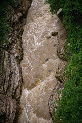 Mountain river after rain. Dirty stream with rapids. Natural landscape.