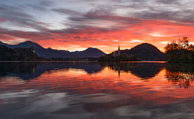 Lake Bled at Sunrise. Church, castle and the mountains are basking in the morning autumn sun