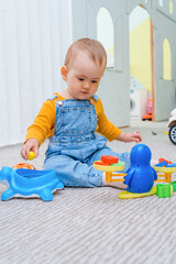 A small child is playing with toy scales sitting on the floor in the playroom